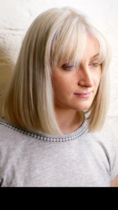 lady stood again white brick wall with blonde hair